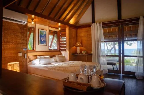Inside a Green Lodge bungalow &mdash; woven walls, a high pitched wooden ceiling, and sliding doors onto a deck above the water